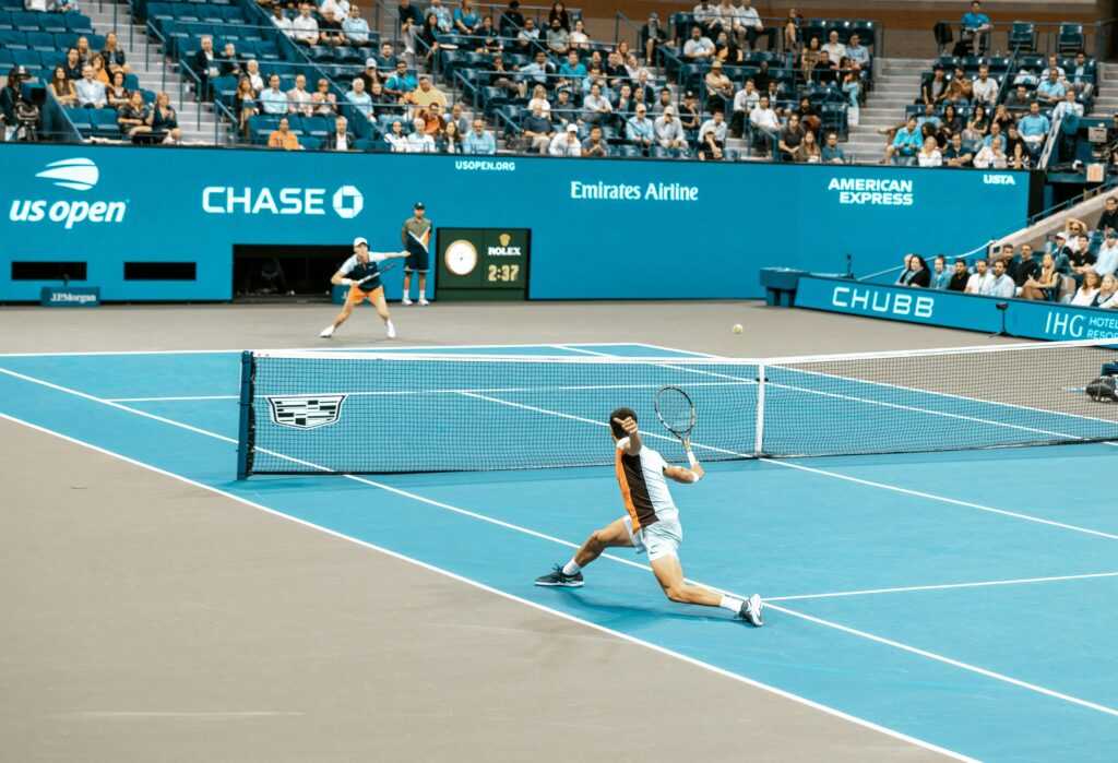 Dynamic scene of players in action at the US Open on a bright tennis court.